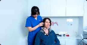 Audiologist fitting headphones on a patient for a hearing test
