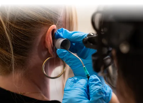 Audiologist performing ear wax removal