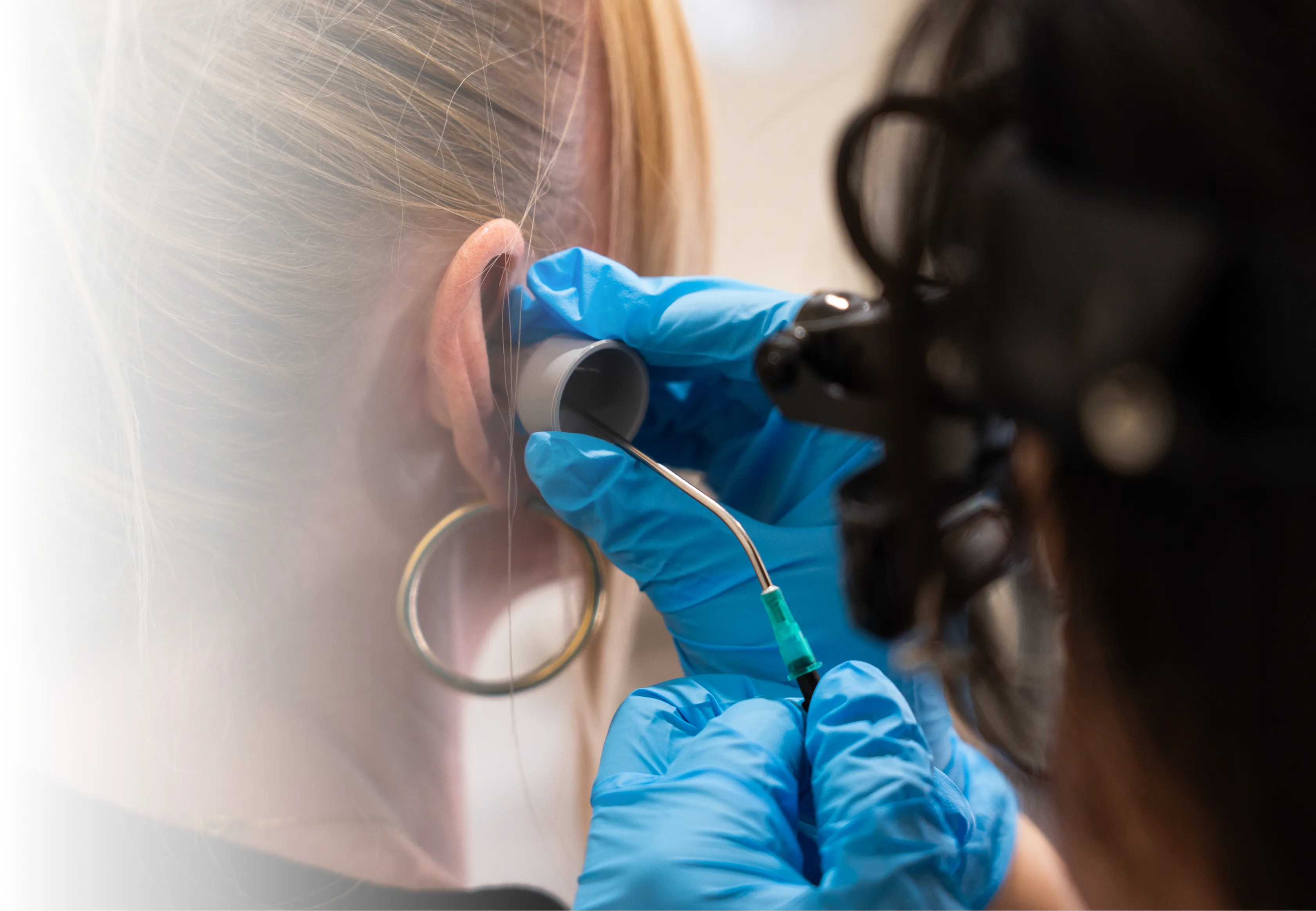 Audiologist performing ear wax removal